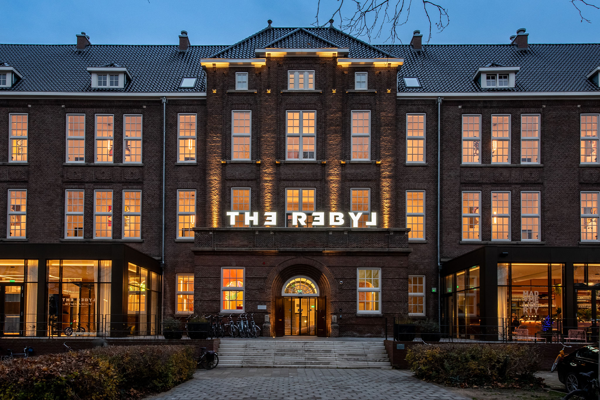Verlichte gevelletters van The Rebyl op een monumentale bakstenen gevel